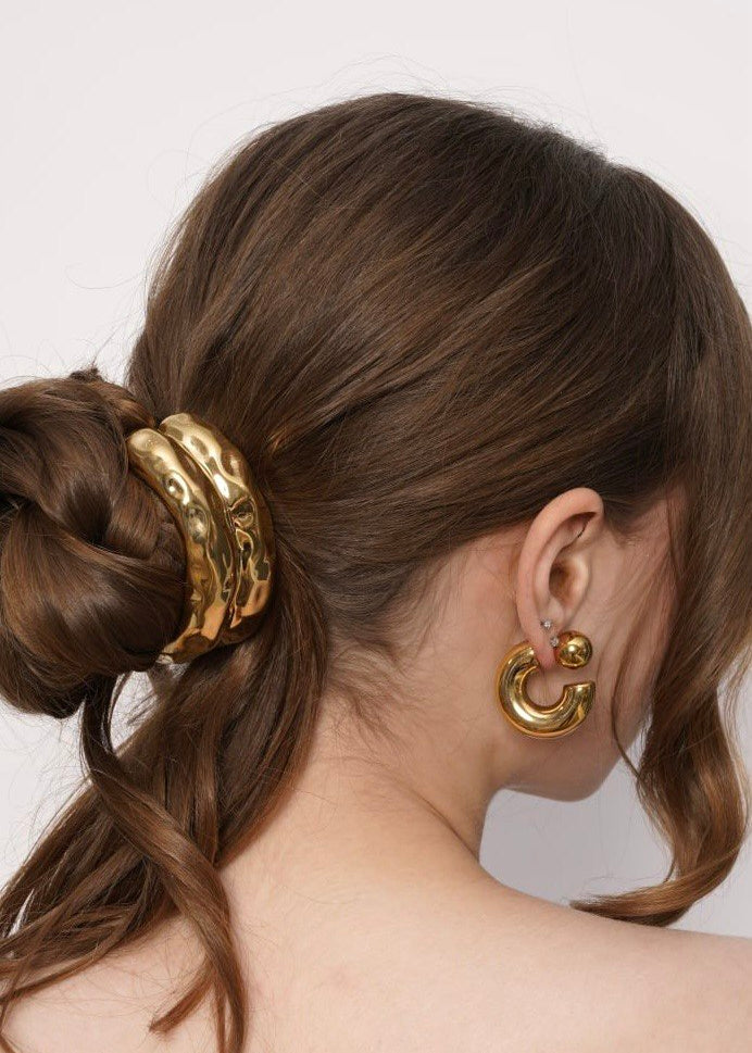 Model wearing Celeste gold hoop earrings with a gold hammered ponytail cuff, Luvertta